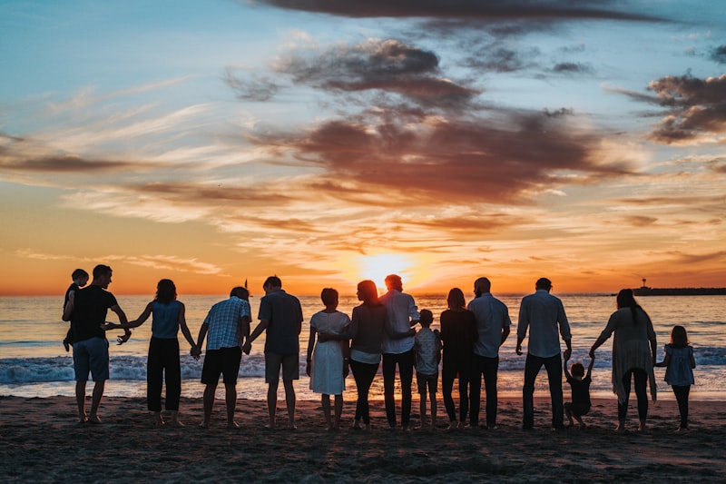 An extended family holding hands together on the beach at sunset